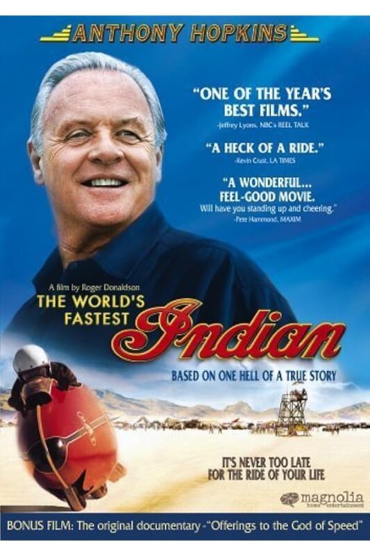 Smiling older man above a vintage motorcycle poster